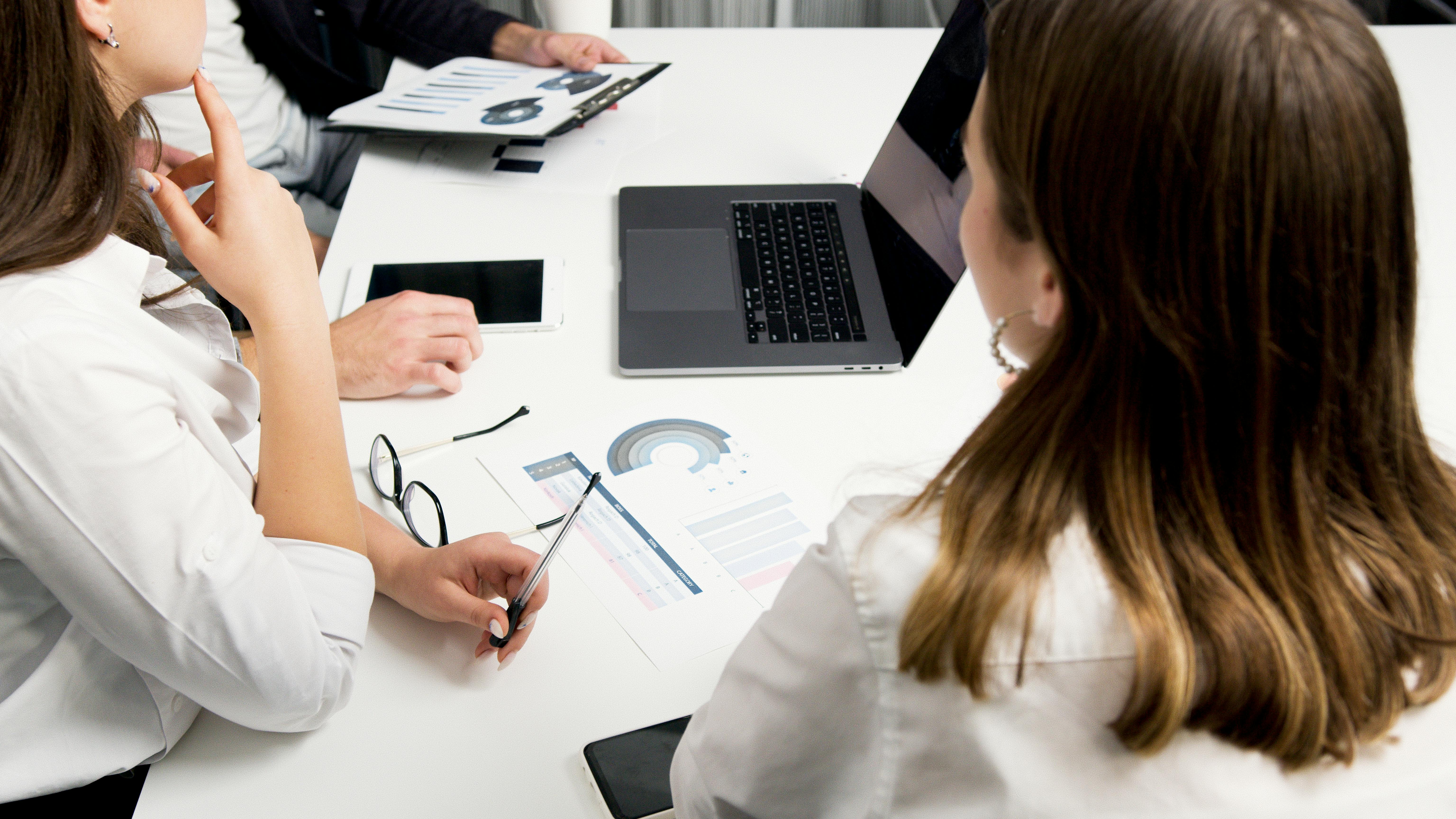 Three people at a desk working in government contracting.