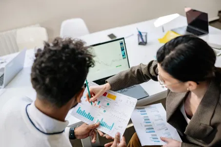 Two professionals reviewing performance dashboards and printed charts to support collaborative data-driven decision-making in the government. Photo by Yan Krukov via Pexels.
