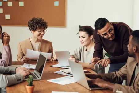 Team collaborating around data dashboards and website design during a strategy meeting to improve customer service experience. Photo by Fauxels via Pexels. 
