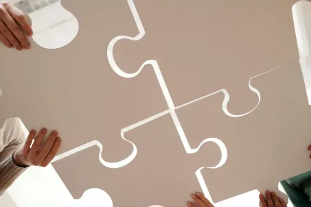 Team members holding large puzzle pieces symbolizing collaboration in organizational change management. Photo by Diva Plavalaguna.