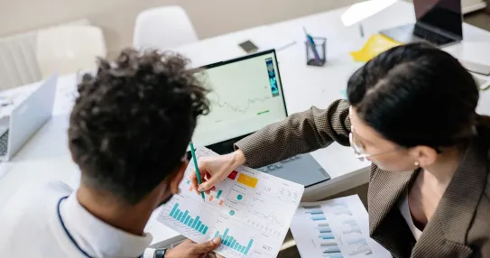 Two professionals reviewing performance dashboards and printed charts to support collaborative data-driven decision-making in the government. Photo by Yan Krukov via Pexels.
