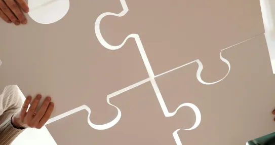 Team members holding large puzzle pieces symbolizing collaboration in organizational change management. Photo by Diva Plavalaguna.