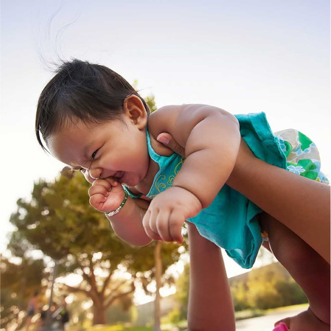 hands holding smiling baby in air